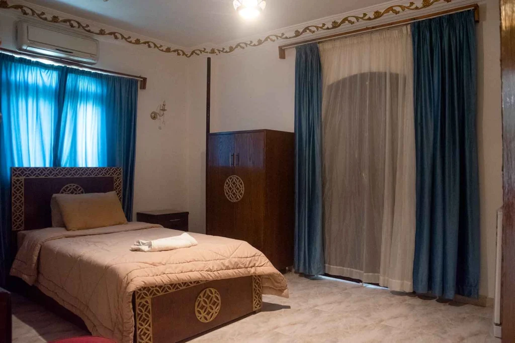 Cozy single room with comfortable bed and traditional wooden wardrobe in Luxor