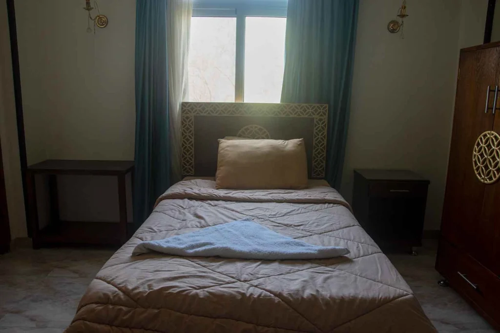 Cozy single room with comfortable bed and traditional wooden wardrobe in Luxor